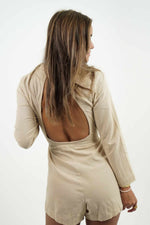 Beautiful bare back on a beige linen jumpsuit. It has a blazer style neckline and a fitted belt at the waist.