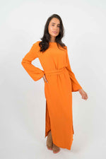 Long orange backless dress with long sleeves. Can be belted at the waist and is split on the left side.