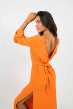 Orange long dress, with a large bare V-shaped back. With long sleeves. It can be belted at the waist and is split on the left side.