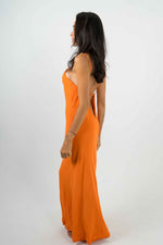Long orange dress with a plunging bare back. It is split on the left side revealing your leg. Thin straps.