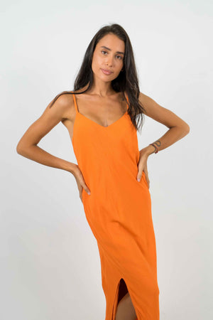 Long orange backless dress. With a slit on the left side. Thin straps.
