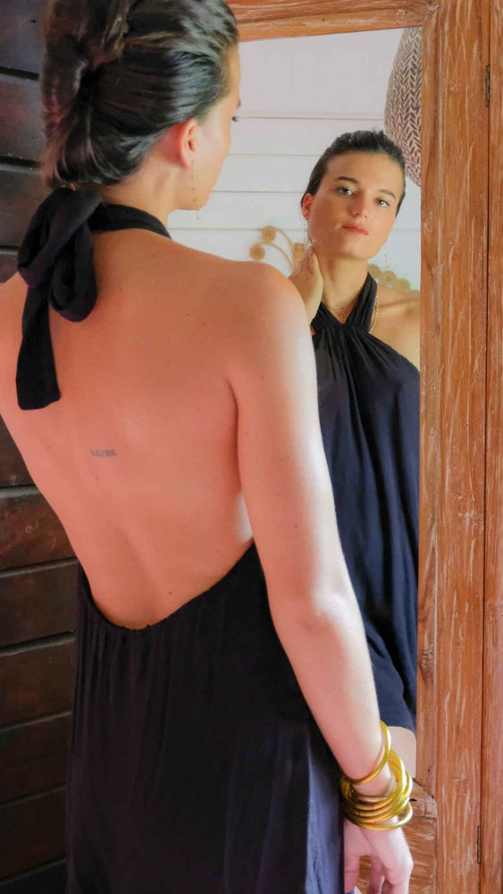 Backless mini dress in black. It is lined and adjustable with a knot that tightens in the neck. Large plunging bare back.