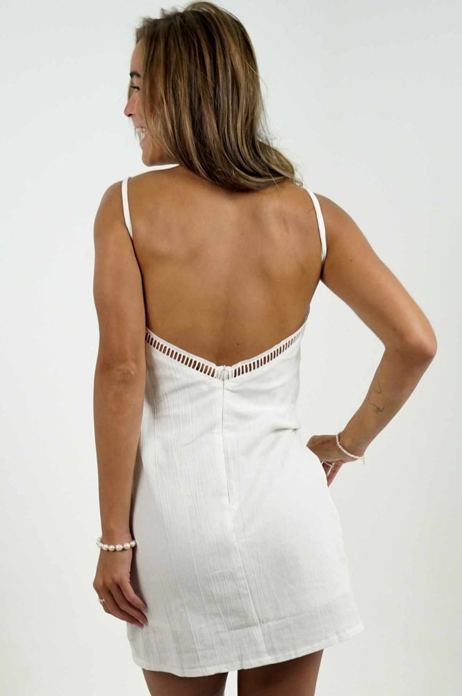 Beautiful bare back of a short dress in white linen. It has details all over the front of it.