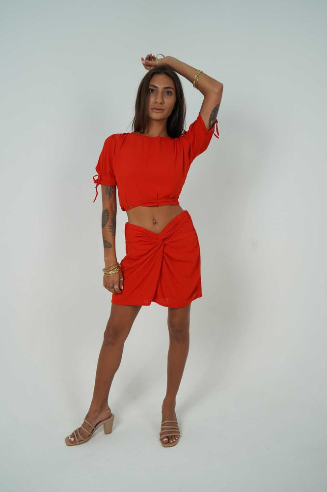 Woman wearing Back Cartel set in a passionate red colour. We love to see her belly button, but you can also wear it higher to hide it.