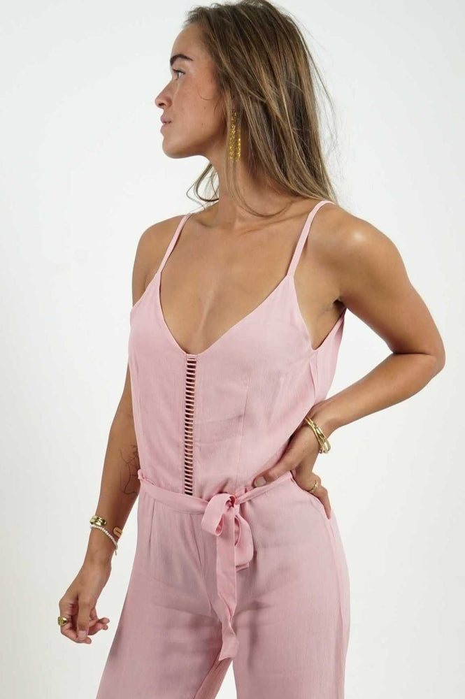 Backless pink jumpsuit with a straight cut. The lower legs are flared, in a fluid and light material. Adjustable belt.
