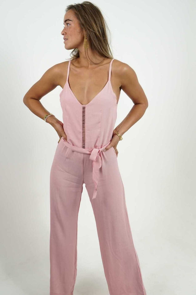 Backless pink jumpsuit. It has a straight cut and flared lower leg, in a fluid and light material. Adjustable belt.