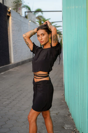 Woman wearing Jack open back top and Rose short skirt set in black 