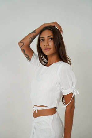 Woman with tattoo wearing puff sleeve white top with adjustable laces